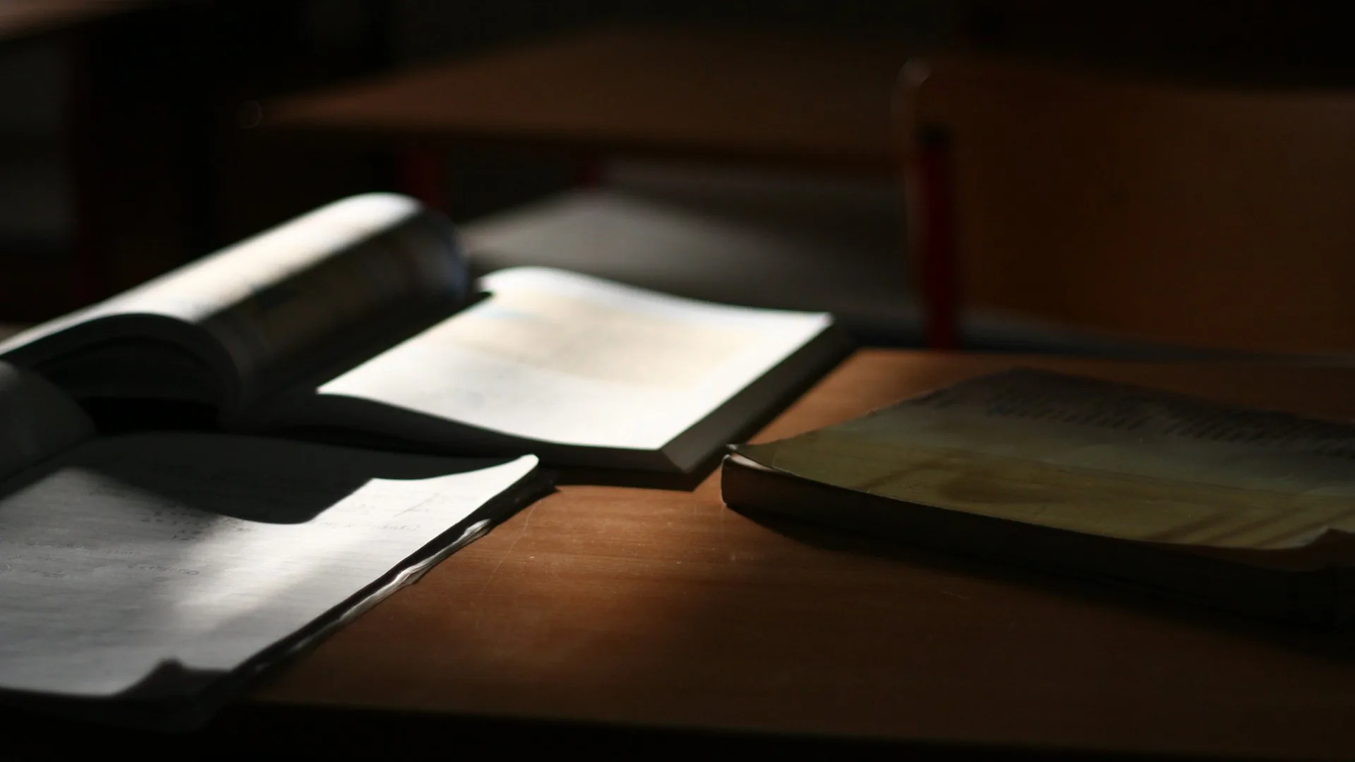 Open books and papers on a desk in low light